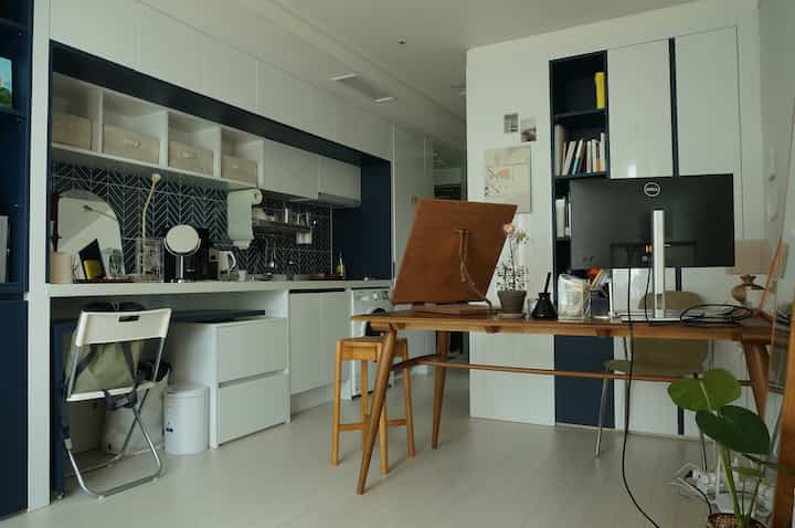 Compact home office space in white and navy tones featuring a wooden desk and furniture with a simple natural vibe