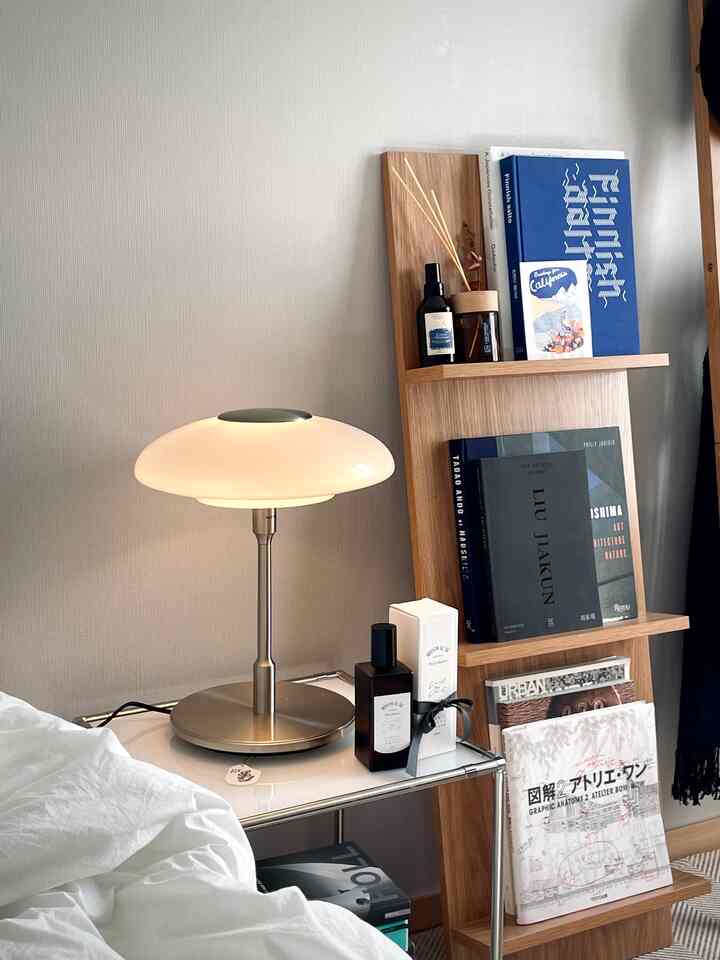 Compact single household room in white and wood tones, featuring bookshelf and table lamp with simple design