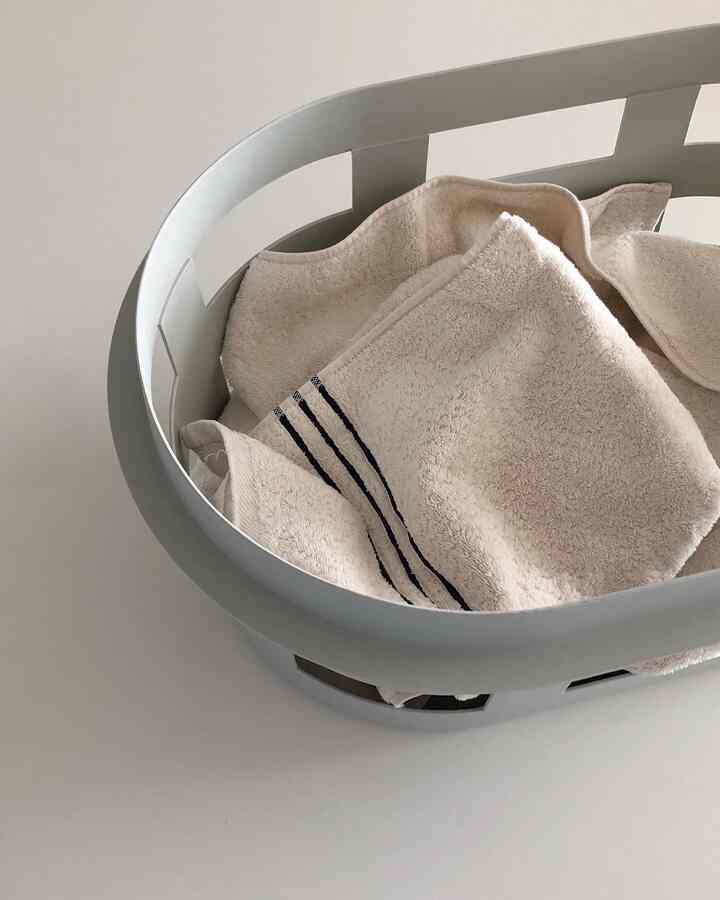 Natural tone simple interior element featuring beige towels in a gray basket