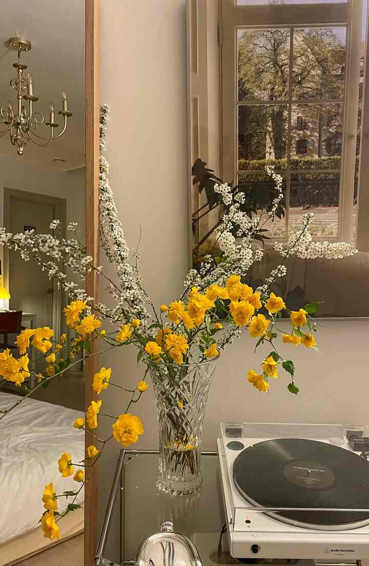 White and yellow-themed living room featuring a modular shelf with a turntable and vase, creating a modern natural atmosphere