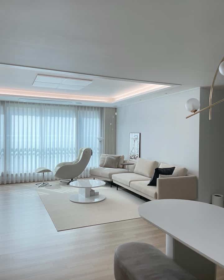 白とベージュの色調のリビング、リニアソファとアームチェアが配置されたシンプルモダンな空間