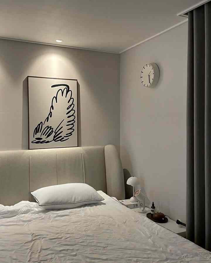 Beige and white toned bedroom featuring large bed and abstract picture frame, creating a simple modern atmosphere