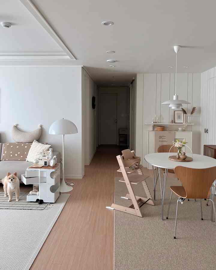 白と木目調のリビングダイニング、犬と赤ちゃん用の椅子が配置されたナチュラルモダンなインテリア