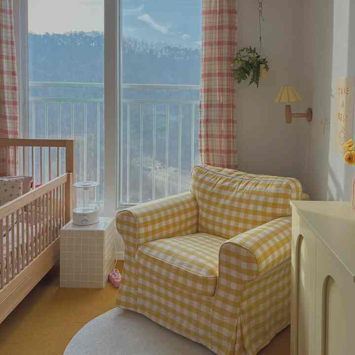 Bright yellow and natural toned kids' room featuring a checked armchair sofa and wooden crib creating a cozy atmosphere