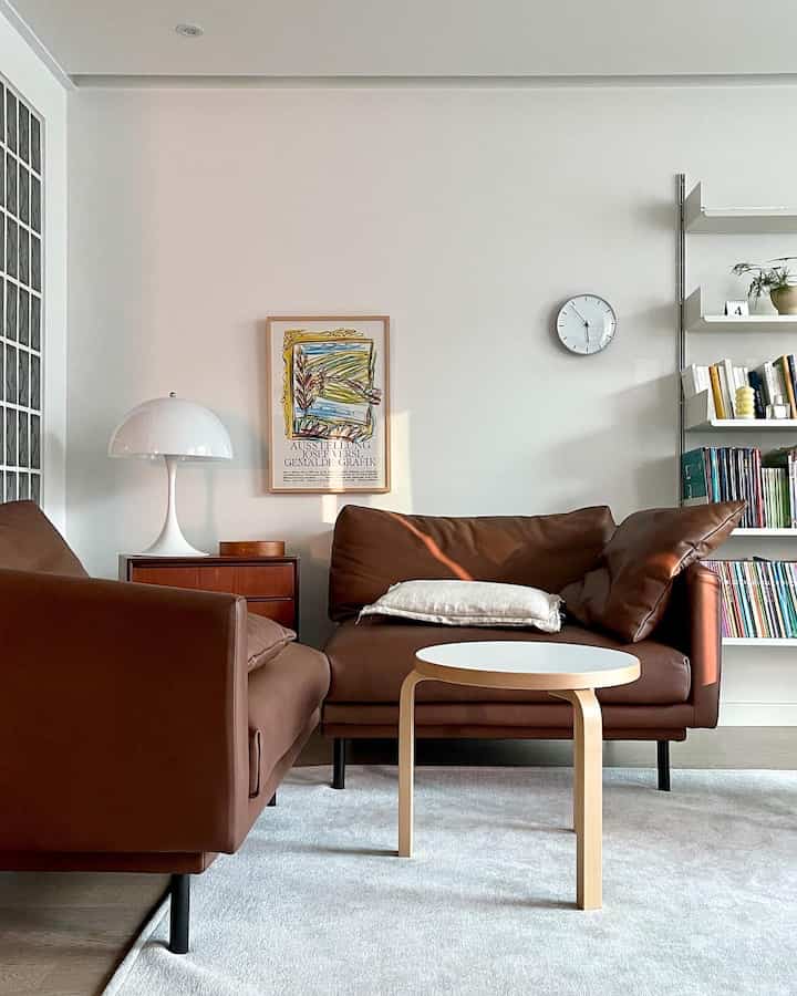 Modern living room with white walls and brown leather sofas, bright and calm atmosphere