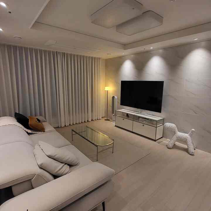 White and brown toned living room featuring a large sofa and TV stand with a modern atmosphere