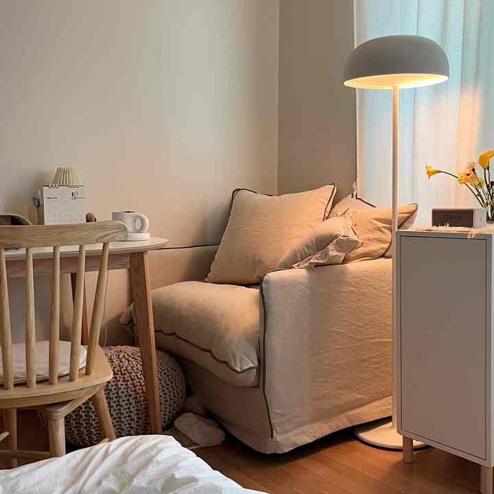 Beige and brown toned small room featuring single beige armchair sofa and wooden chair with warm atmosphere