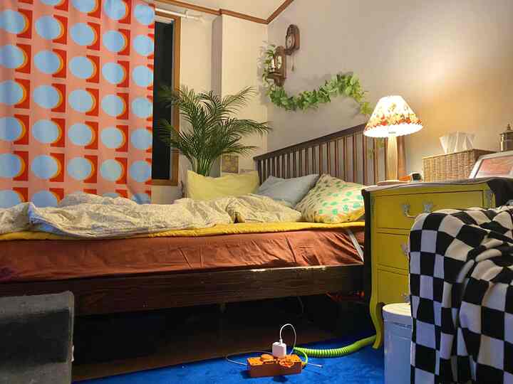 A vivid orange and sky-blue patterned curtain bedroom featuring a wooden bed and yellow nightstand, creating a cozy natural atmosphere