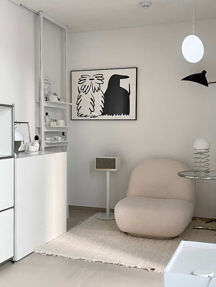 White and monotone living room featuring a soft curved lounge chair and black-and-white poster, creating a simple and modern atmosphere