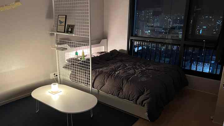White and charcoal toned bedroom featuring a navy rug and warm table lamp for a cozy atmosphere