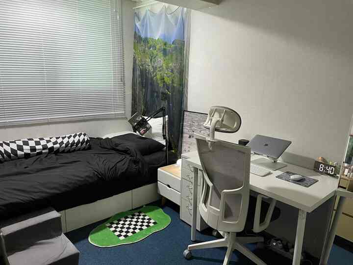 白と黒のトーンの寝室、シングルベッドとデスク、ミニマルなホームオフィスが配置されたコンパクトな空間