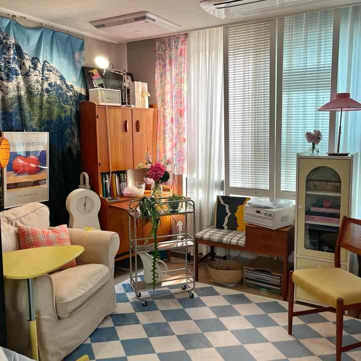 暖かい木目調とフロアランプ、ブラインドがある居心地の良いリビング、ヴィンテージ家具と植物が調和したカフェ風のインテリア