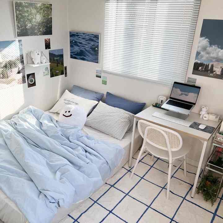 明るいブルーとホワイトの寝室、青い寝具とクッションが配置されたシンプルで居心地の良いインテリア