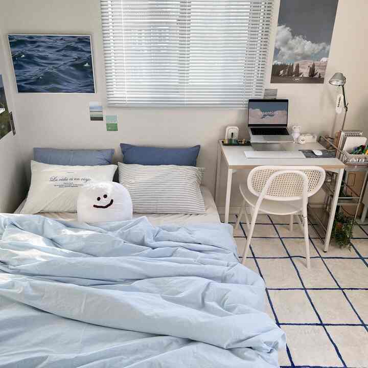 ホワイトとブルーのトーンが調和する一人暮らし向け寝室、シンプルなデスクとブラインドが配置された落ち着いた空間