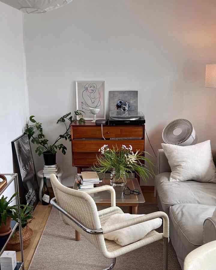 Natural color and wood tone living room featuring cozy sofa, rattan armchair, vase with flowers, and framed artwork creating a warm ambiance