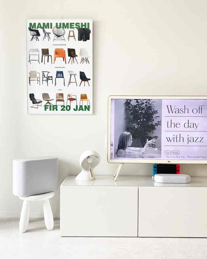 ホワイトトーンのリビングルーム、テレビ台とスツールが配置され、モダンなテーブルランプが調和するシンプルな空間