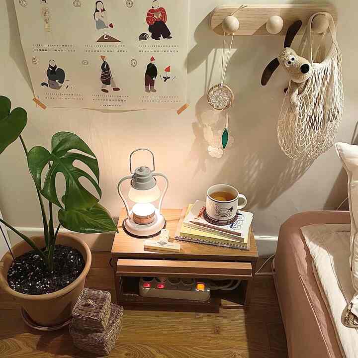 Natural tone bedroom corner featuring a wooden nightstand, a Monstera plant, and a cozy home cafe lamp setup