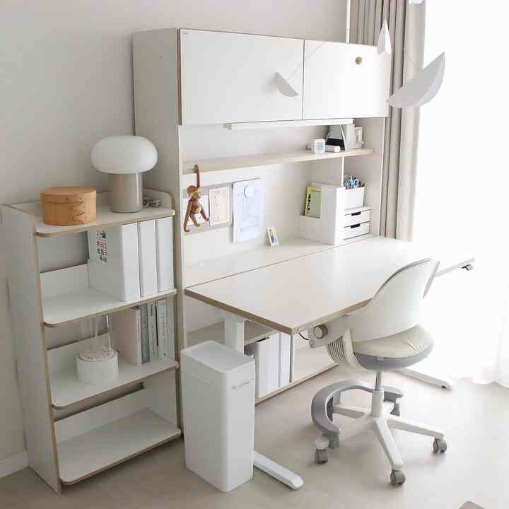 White and natural toned kids' room featuring a desk, bookshelf, storage boxes, and ergonomic chair arranged neatly
