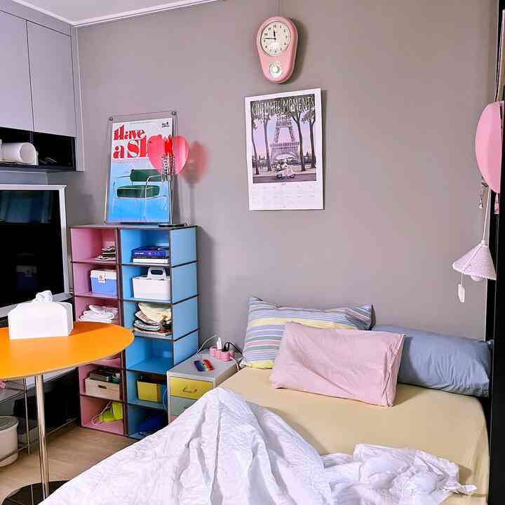 A simple 6-tatami studio apartment featuring pink and blue accents, bedding, and a multifunctional storage shelf