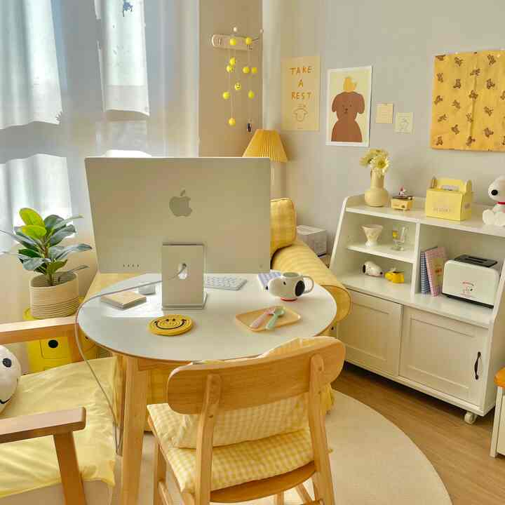 Bright yellow and white toned home office space featuring a round desk, yellow sofa, and cute dog poster creating cozy room