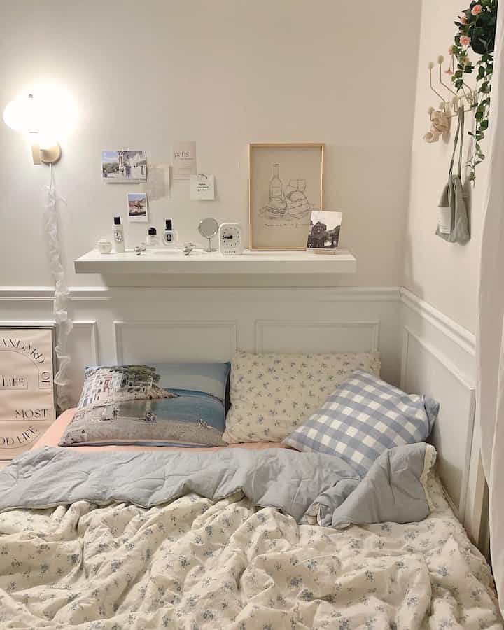 白を基調としたナチュラルな寝室、枕と柄の掛け布団が配置された温かみのある空間