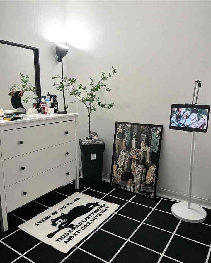 黒と白のトーンのワンルーム寝室、白黒の格子柄ラグと白いチェストが配置されたミニマルなインテリア