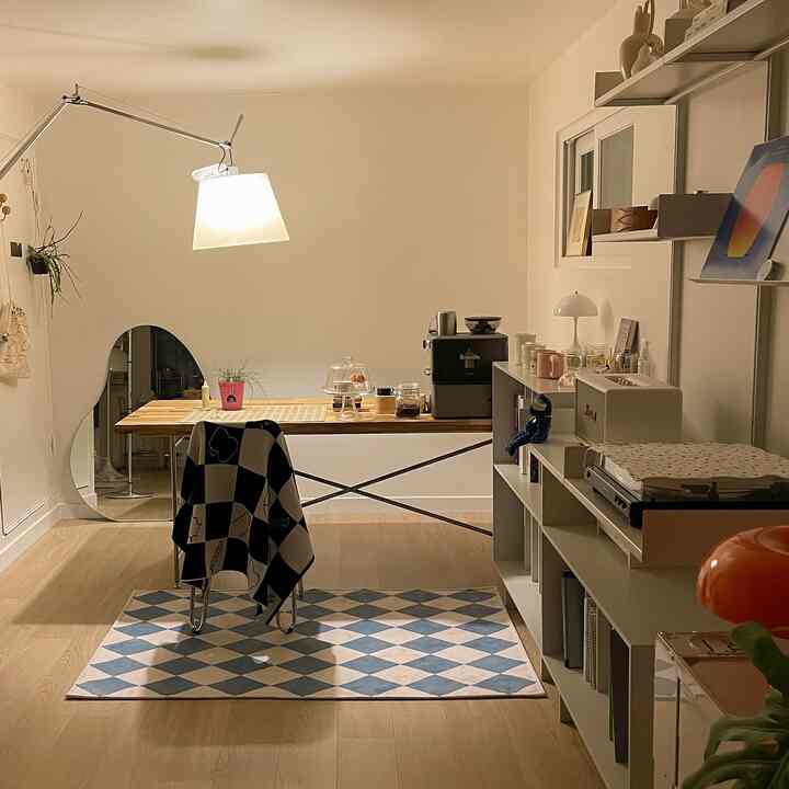 Natural wood toned home office with white walls featuring coffee equipment and table lamp in a cozy and tidy workspace