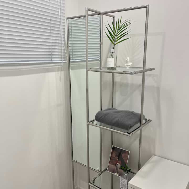 White-toned walk-in closet featuring steel shelving and a full-length mirror with towel and decorative sculpture for a clean interior