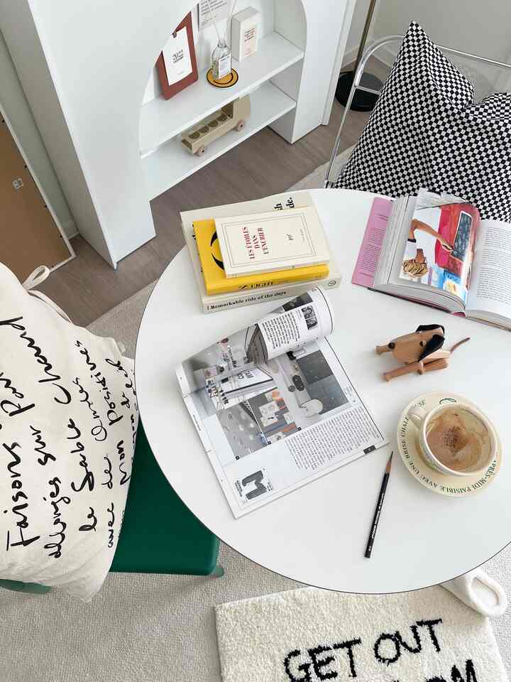 White and green toned dining room featuring a round table, checkered cushion, and decorative objects in a simple cozy setting