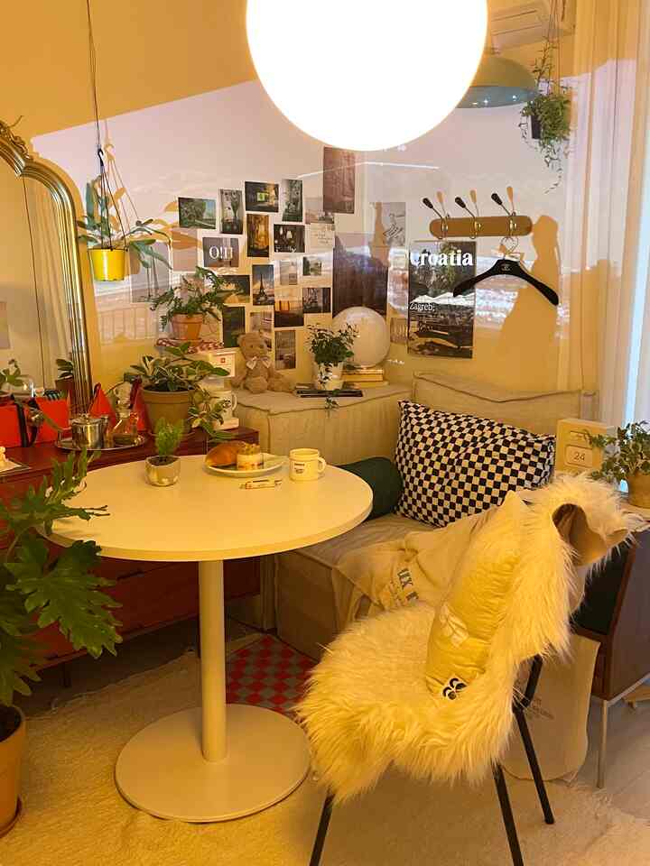 黄色と白を基調としたリビング、丸テーブルと多彩な植物が配置された雰囲気のあるインテリア