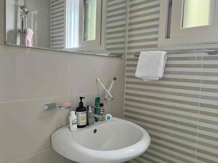 白とグレーの色調のバスルーム、洗面台と歯ブラシ、タオルが配置された清潔な空間