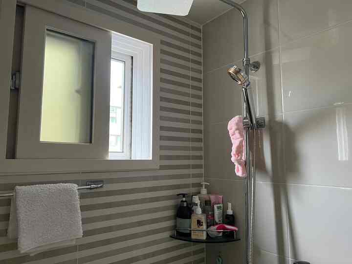 グレーと白の色調のバスルーム、シャワーとタオル、浴室用品が配置された清潔感のあるインテリア