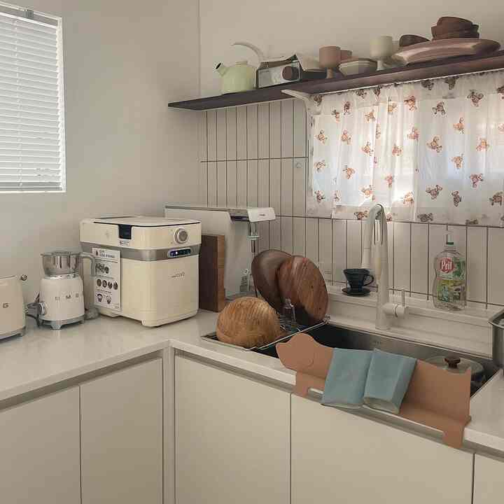 White and wood tone kitchen space featuring SMEG milk frother and blinds with a clean, minimalist interior