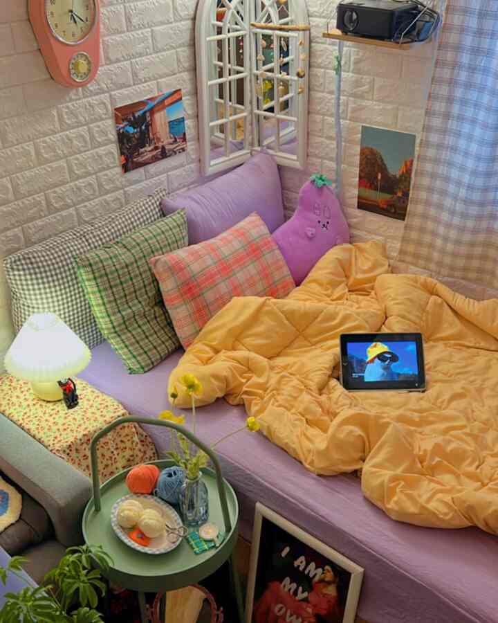 パステル調のラベンダー色ソファベッドと黄色の掛け布団が置かれた、雰囲気のある寝室空間