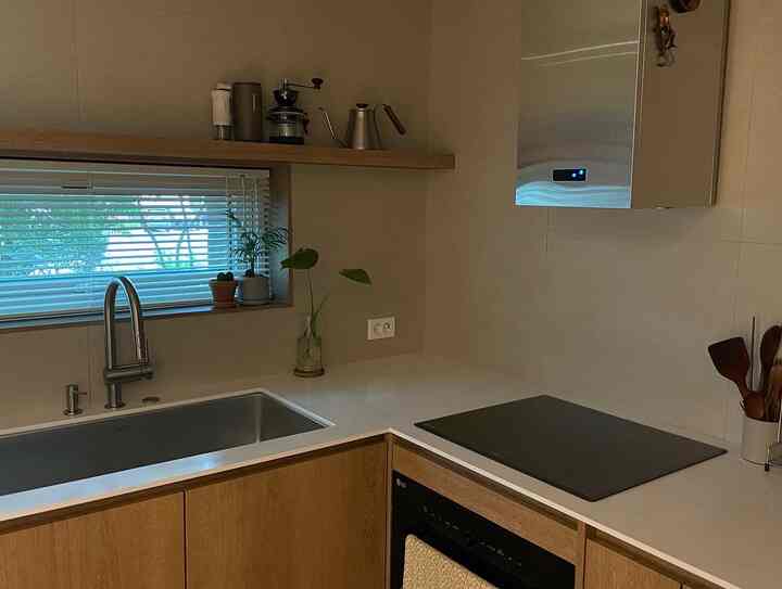 White and wood tone kitchen featuring a sink, induction cooktop, and horizontal blinds neatly arranged