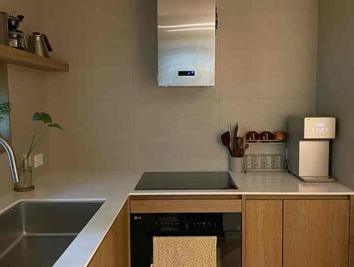 Simple kitchen featuring natural wood tone cabinets and white countertops, equipped with induction cooktop and water purifier appliances