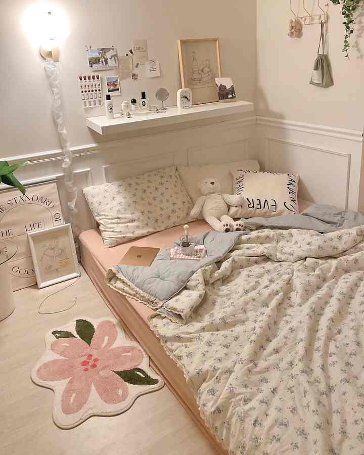 柔らかなピンクとナチュラルな色調の寝室、花柄の寝具とピンクの花の形をしたバスマットが置かれた温かみのある空間