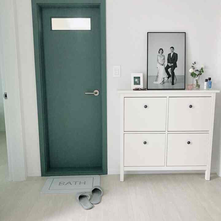 ホワイトとナチュラルトーンの浴室前スペースに、イケアのコンソールとグレーのバスマットが配置された雰囲気のあるインテリア