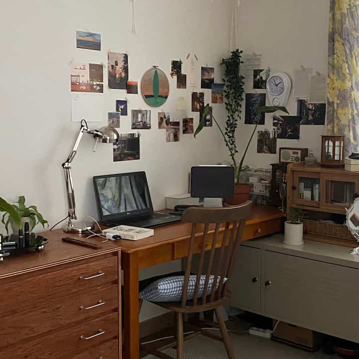 Natural-tone home office with white walls and wood furniture, decorated wall artworks creating cozy atmosphere