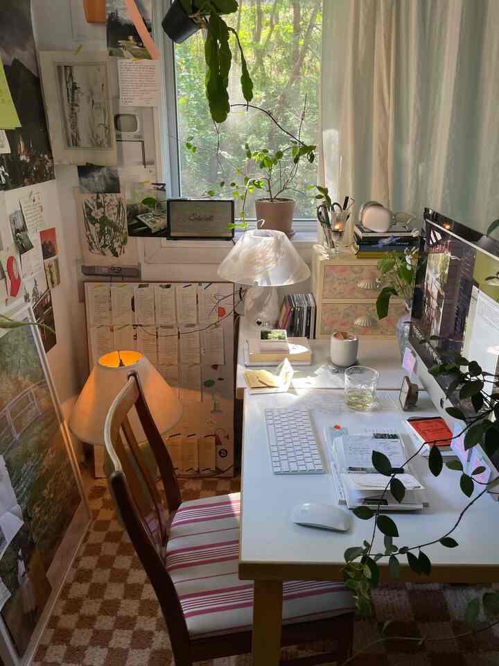 White and brown toned home office space featuring a desk, office chair, and several plants creating a warm working atmosphere