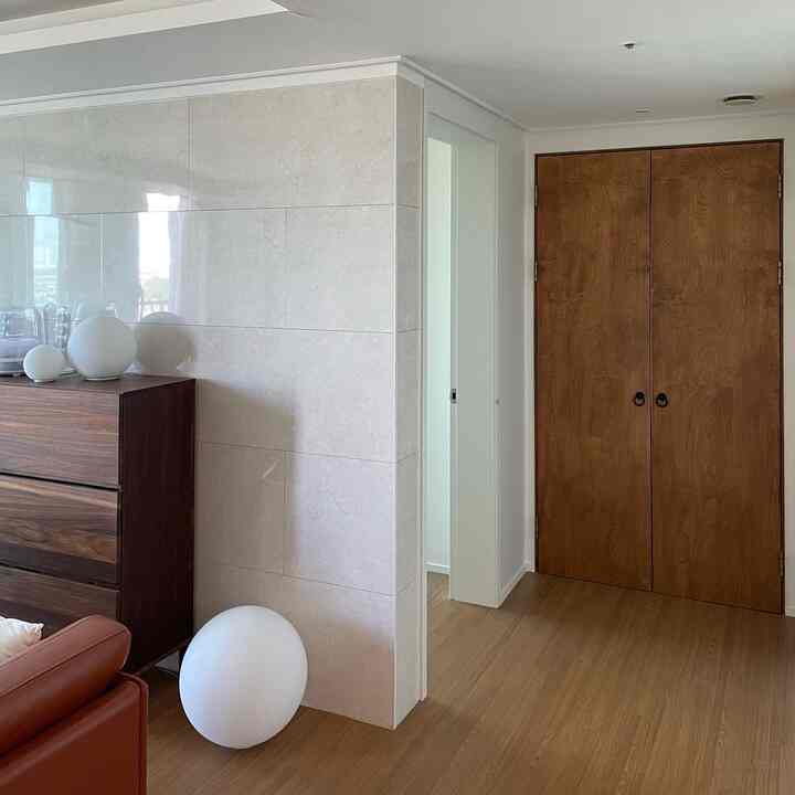 ブラウンの木目調とホワイトを基調としたリビング、両開きの木製ドアと収納キャビネットが配置された落ち着いた印象の空間