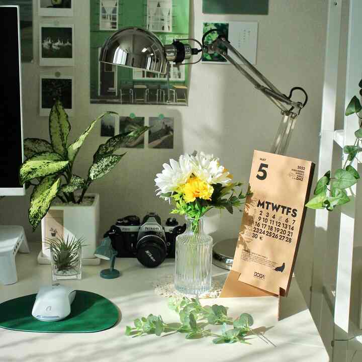 Bright white-toned home office space featuring a desk with artificial flower vase and desk lamp in a modern interior