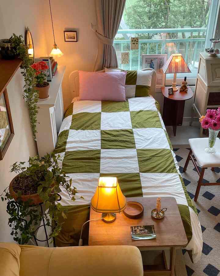 Natural tone studio bedroom featuring checkered bedding, nightstand with lamp, creating a cozy atmosphere