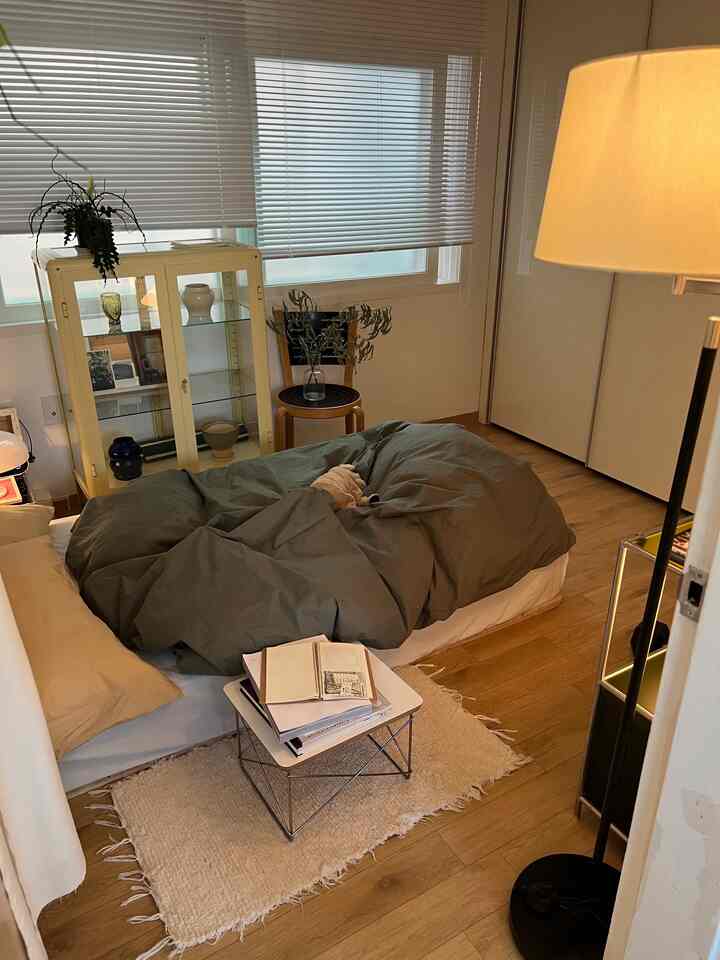 Natural modern bedroom in beige and khaki tones featuring bed, rug, and floor lamp with cozy atmosphere