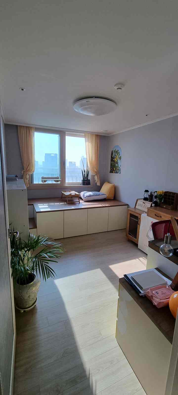 Beige and natural tone small room featuring a floor bed with storage by the window, cozy home cafe setup