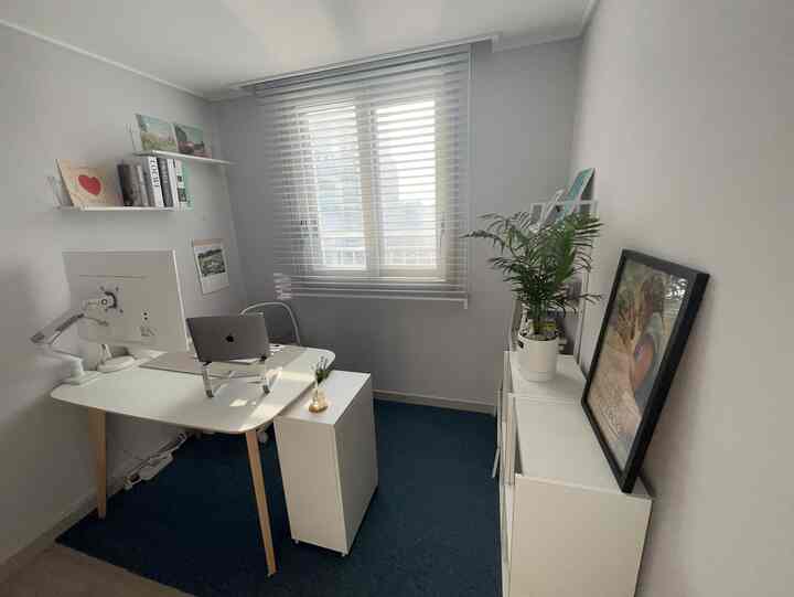 白と青のトーンのホームオフィス、清潔なデスクとコンピューター設備、観葉植物が配されたシンプルでモダンな空間