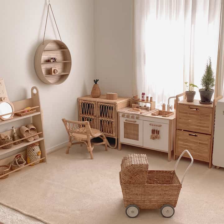 Natural wood and rattan furniture arranged in a kids' playroom for babies and children, featuring soft beige rug and lightweight curtains creating a cozy atmosphere