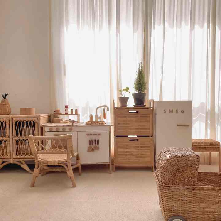 Natural-toned kids' room featuring rattan furniture and a charming toy kitchen set with a warm atmosphere