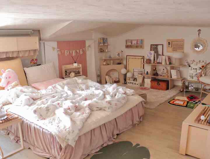 ピンクと木目調が調和するロフトの寝室、かわいい小物と低い勾配天井が印象的な居心地の良い空間