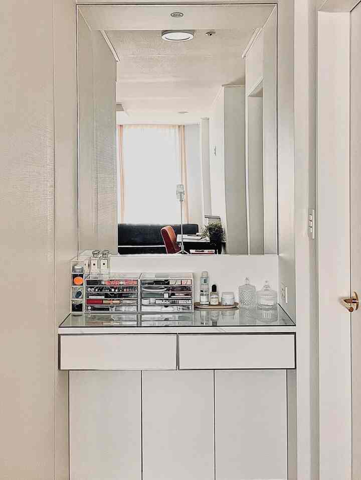 Bright white bedroom with a vanity featuring transparent acrylic storage boxes for organized cosmetics